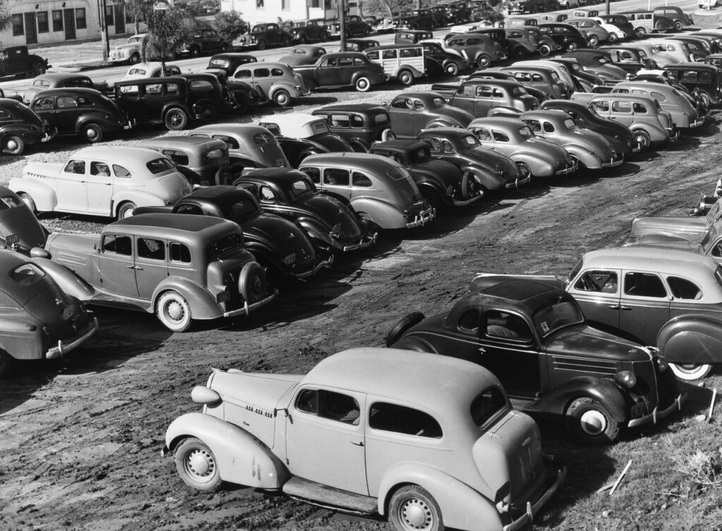 Russell Lee (1903 - 1986). Workers' automobiles parked rear the airplane factories. Providing parking space for automobiles and getting the cars in and out at shift-changing time have been big problems. San Diego, California. December 1940.