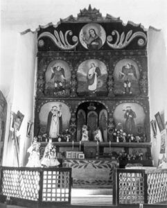 John Collier Jr. (1913 - 1992). Main altar of painted wood in a church which was built in 1700, and is the best-preserved colonial mission in the Southwest. There is an older altar behind the wooden one which is painted directly on the adobe wall. Trampas, New Mexico. January 1943.