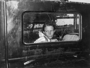 Russell Lee (1903 - 1986). Migrant worker looking through back window of automobile near Prague, Oklahoma. Lincoln County, Oklahoma. June 1939.