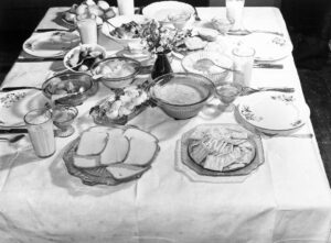 Marion Post Wolcott (1910 - 1990). A family supper at the home of Mr. and Mrs. Helm, consisting of roast beef (home canned), turnip greens, potato salad, stuffed eggs, lima beans, rice, pickled pears, biscuits, cornbread, butter, milk, peaches and cake. Coffee County, Alabama. March 1939. Gift of Bette Winthers.