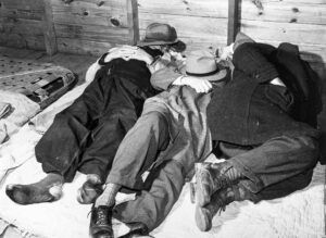 Marion Post Wolcott (1910 - 1990). Farmers sleeping in a white camp room in a warehouse. They often must remain several days before their tobacco is sold. Durham, North Carolina. November 1939.